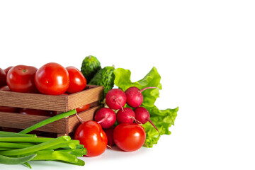 Tomatoes, radishes, green onions, cucumbers and lettuce in a wooden box. Isolated on white background.