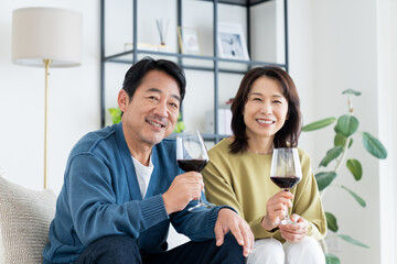 リビングでワインを飲むミドルの夫婦
