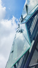 Futuristic glass building facade with reflections against blue sky