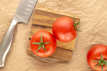 Red juicy tomatoes on kraft paper, close-up, top view.