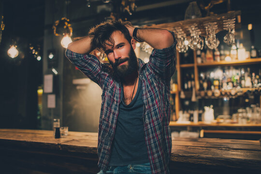 Attractive young man posing for the camera at the bar. Attractive hipster, brutal bearded man in good physical shape, portrait