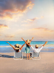 A happy family on summer holidays sits on a tropical beach and enjoys together the beautiful sunset