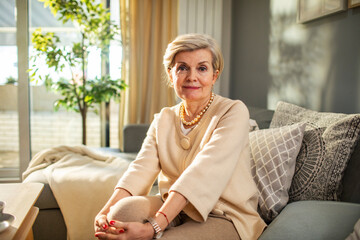 Portrait of a smiling senior woman standing in cozy modern living room