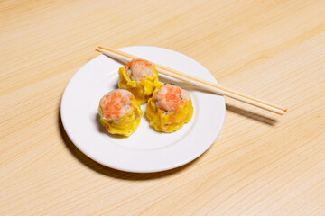 Dimsum on white plate isolated on wooden background
