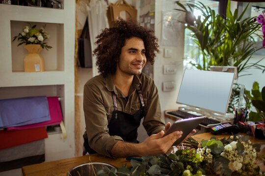 Young male florist using digital tablet at flower shop counter