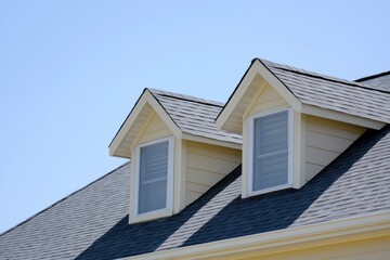 House Exterior. Roof Windows. Second floor among blue sky. Mansard attic. Newly build houses. Gable roof with skylight, asphalt roofing, shingles. Residential Home. Vinyl Siding. Polymeric roof-tiles