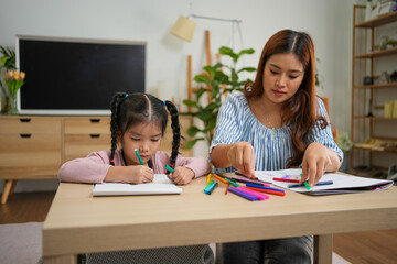 Fototapeta premium Young girl and woman drawing with colorful markers at table in cozy room with plants and shelves
