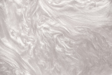 Shimmering silver abstract background. Liquid glitter paint texture waves and swirls. Beautiful shiny white glitter texture. Metallic silver paint close-up as a holiday background.