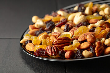 Mix of dried nuts and raisins on a black background.