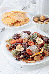Mix of dried tropical fruits, nuts, and raisins on a white table.