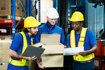 Team of diverse warehouse workers wearing reflective safety vests and helmets inspecting goods from cardboard box discussing checklist using laptop cooperation trust teamwork warehouse management