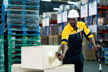 African warehouse worker wearing safety helmet and yellow uniform using barcode scanner scanning box during inventory check industrial logistics process shipping supply chain warehouse teamwork
