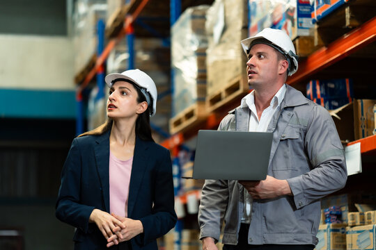 Warehouse teamwork between female supervisor and male worker inspecting packages and checking stock using laptop during warehouse operations logistics management supply chain industrial diversity