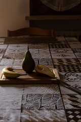 Preparing healthy fruit: Pear, banana, cut pear on wood board, knife ready. Dramatic lighting.