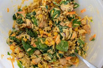 Bowl of food with rice, carrots, and other vegetables. The rice is mixed with a creamy sauce.