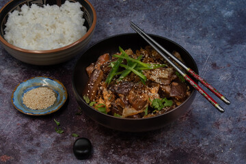 Korean vegan braised eggplant gaji namul  served in dark bowl  along with rice