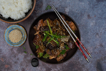 Korean vegan braised eggplant gaji namul  served in dark bowl  along with rice