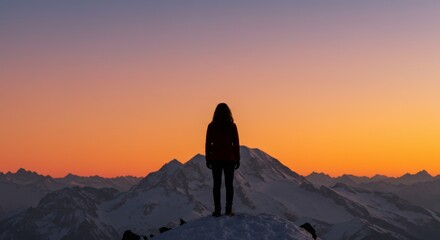 Obraz premium Silhouette of a woman standing on a snowy mountain peak at sunset admiring the stunning landscape and achieving personal success