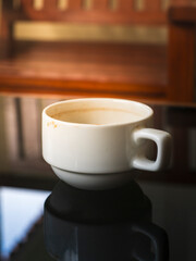 Empty coffee cup with milk foam stains imprint on the edges left on dark glass table of