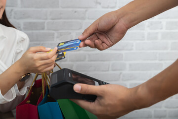Customer woman using credit card for payment. Salesman holding a credit card swipe machine or electronic data capture along with accepting credit cards from customers.