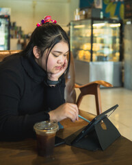 Young business woman manager  asian one person sit on sofa smile cheerful looking and hand holding tablet happiness think idea work new project job online product sale marketing in cafe coffee shop