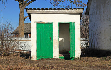 Free public toilet. WC. Capital outdoor toilet in the village. Facade and construction of small toilet. A place of seclusion from people for defecation. Small building for defecation. Double toilet