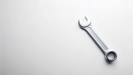 A metallic wrench rests on a smooth, pristine surface, suggesting concepts of repair, maintenance, and problem-solving.