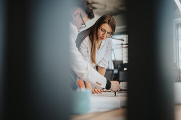 A project leader and colleague working together on documents in a modern office. They are engaged in discussion and collaboration, emphasizing teamwork, focus, and professional dedication.