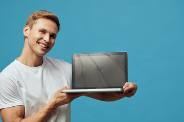 smiling man holding laptop digital nomad casual white t-shirt blue background technology concept