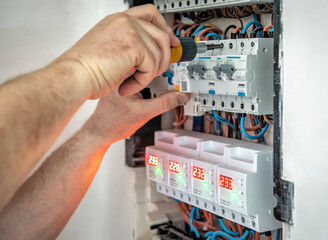Hands of professional electrician with screwdriver tighten up switching electric actuator equipment in fuse box