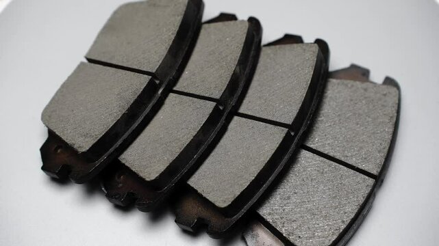 Four brake pads lie next to each other, rotating on turntable. Auto parts replacement concept.