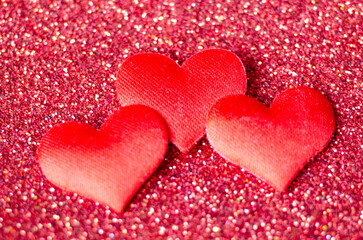 Top view of 3 tiny red hearts on sparkle red background with customizable space for text or wishes