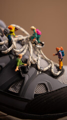 Miniature adventurers climb the laces of a hiking shoe in a whimsical display of exploration and imagination