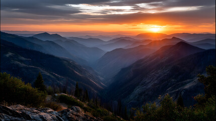 Fototapeta premium The last rays of the orange sunset casting a peaceful glow over the mountain tops and valleys below.