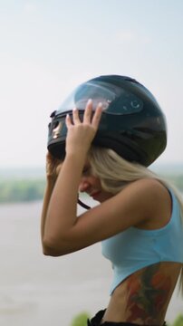 Happy man and young woman in blue top take off protective moto helmets standing against large picturesque lake on spring day slow motion