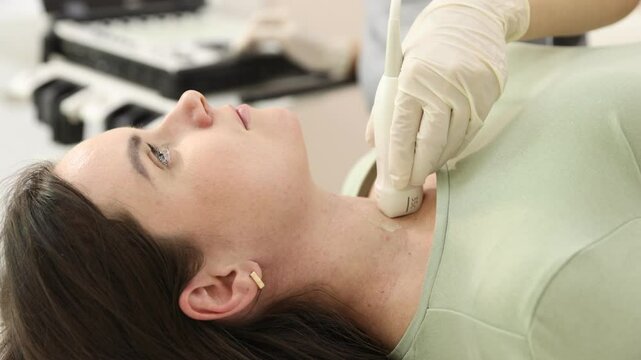 Sonographer conducting ultrasound examination of woman's thyroid gland in clinic, closeup