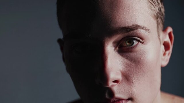 Intriguing Gaze: Half-lit face of a young person, eyes intensely focused, creating a mood of mystery and contemplation.  The shadowed side adds depth and intrigue.