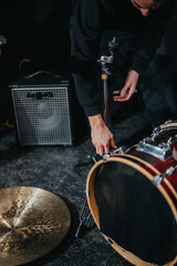 Person adjusts drum equipment in a professional studio, preparing for a musical session. Other...