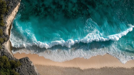 Aerial view of vibrant blue ocean waves crashing on a sandy beach.
