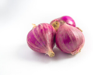 Three red onions with vibrant purple-red hues rest on a white surface. Their outer skins are...