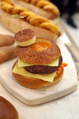 hamburguesa de carne con queso fundido y huevo en pan brioche de semillas y sésamo