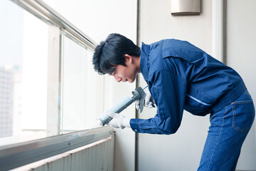 外装工事でコーキング材を塗る作業員の男性