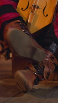 Musician in leather laced boots prepares to play igil with bow at ethnic concert on stage closeup. Siberian musical instruments. Culture and art