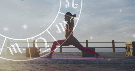 Image of horoscope over biracial woman stretching on promenade