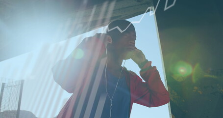 Statistical data processing against african american fit man wearing earphones outdoors
