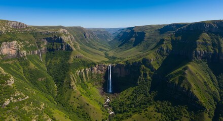An awe-inspiring waterfall cascades down a lush green cliff into a vibrant valley.