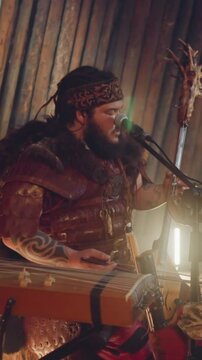 Frontman of folk rock band plays bow instrument singing by throat on stage in ail. Shamanic rituals and music show. Siberian meditative sound
