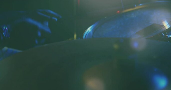 Drummer playing snare drum under cool blue and green stage lights, with animated waveform overlay