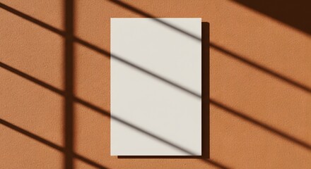 Fototapeta premium AI image features a blank vertical paper mockup placed on a terracotta textured wall, crossed by distinct window blind shadows.