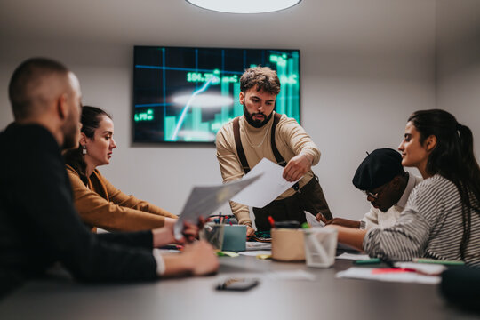 A collaborative team working during a meeting, analyzing financial data. People are actively discussing charts, showcasing a professional workspace and innovative ideas.